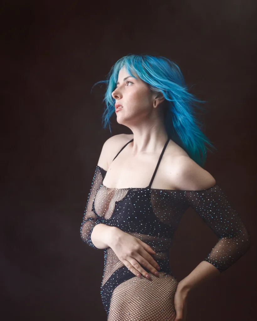 Person with blue hair in sparkly mesh outfit.
