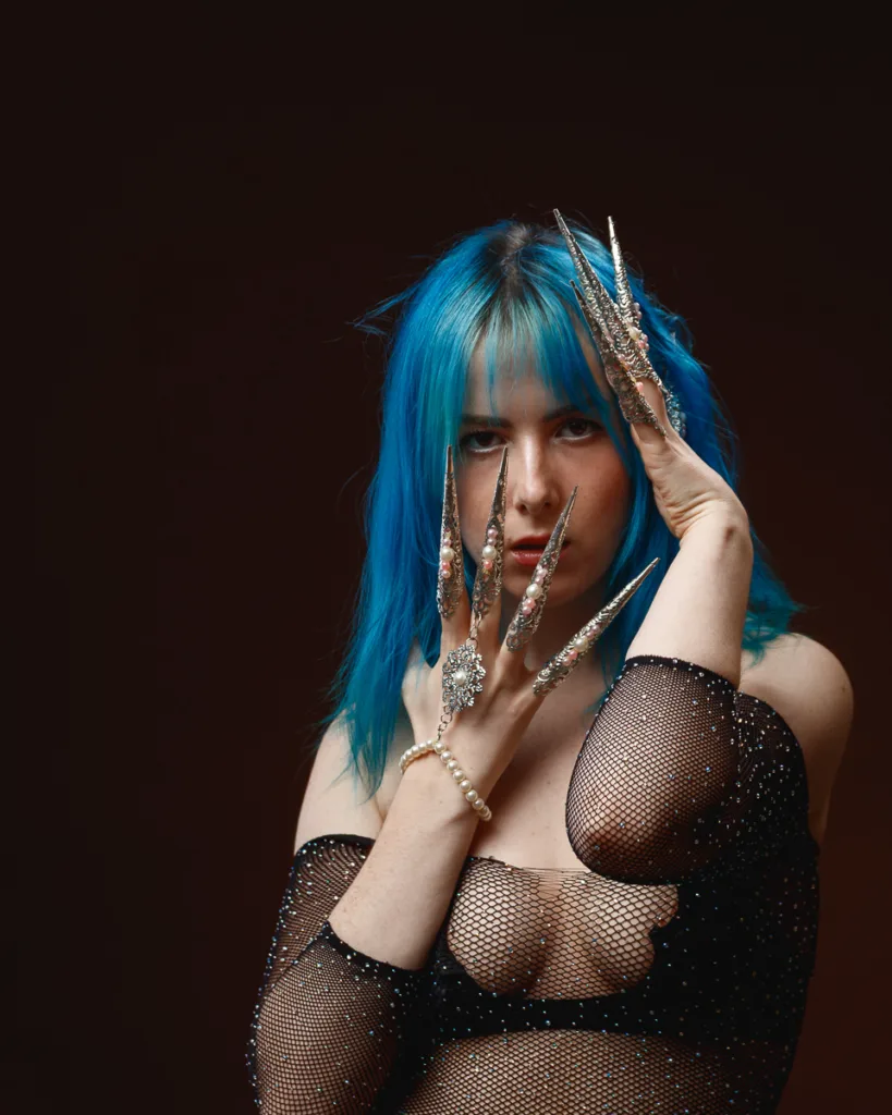 Woman with blue hair and ornate nails.