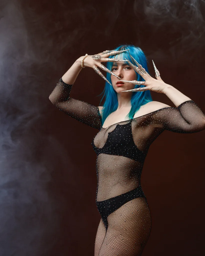 Fashion model with blue hair and dramatic nails.