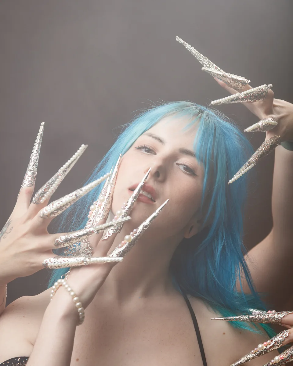 Woman with blue hair and ornate long nails.