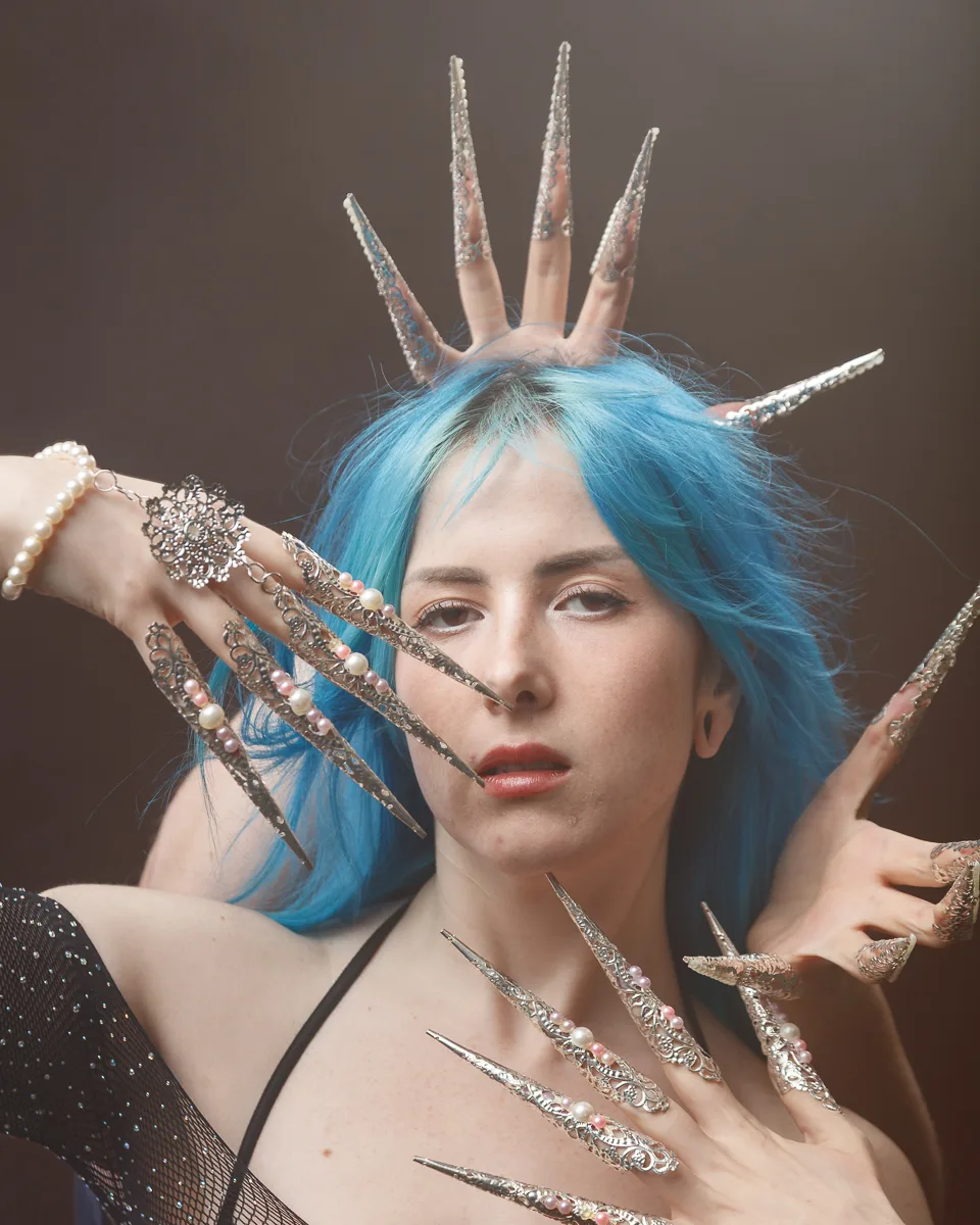 Woman with ornate silver nails and blue hair.