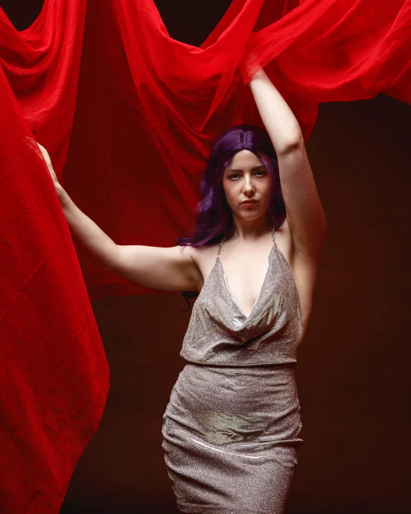 Woman in silver dress with red draped fabric.