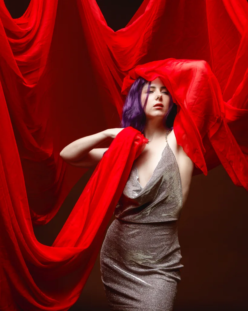 Woman in silver dress surrounded by red fabric