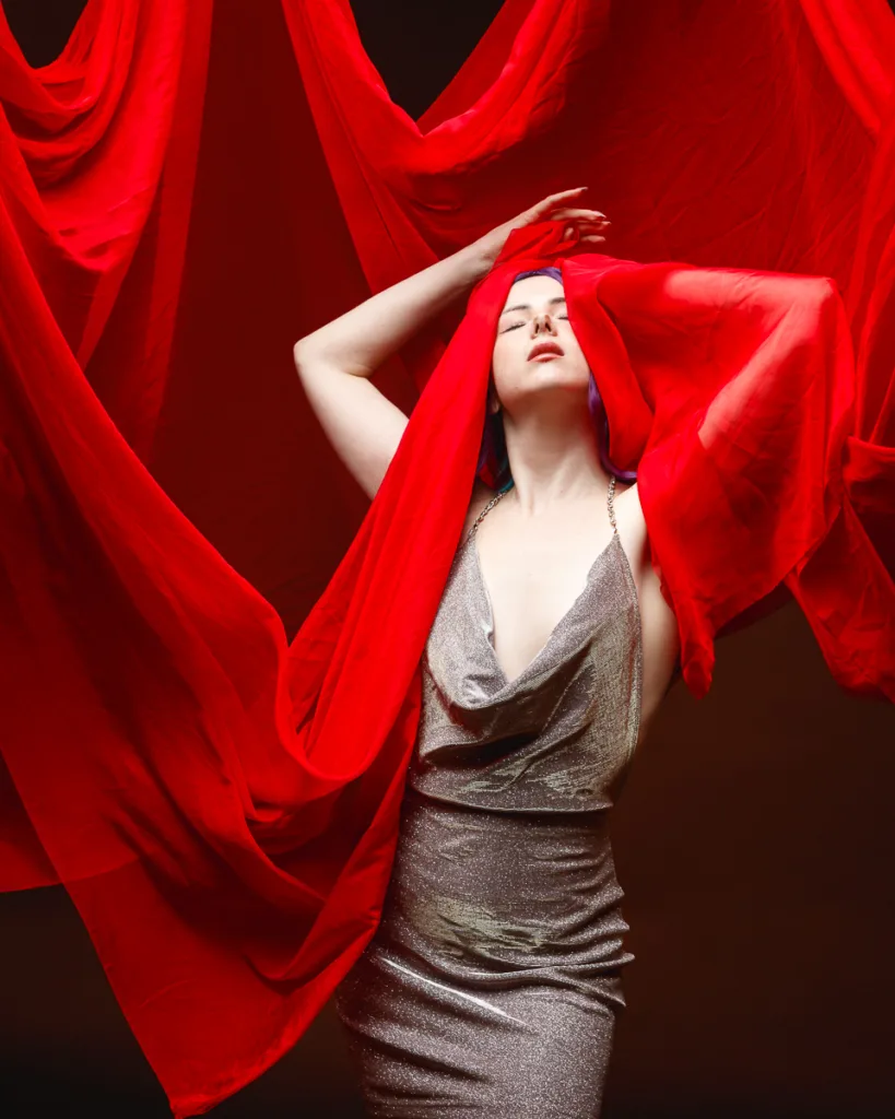 Woman in red fabric, silver dress, dramatic pose