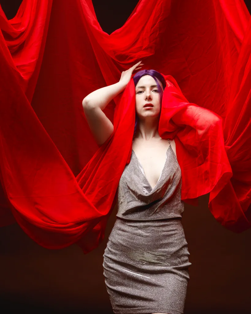 Woman in silver dress with red fabric background.