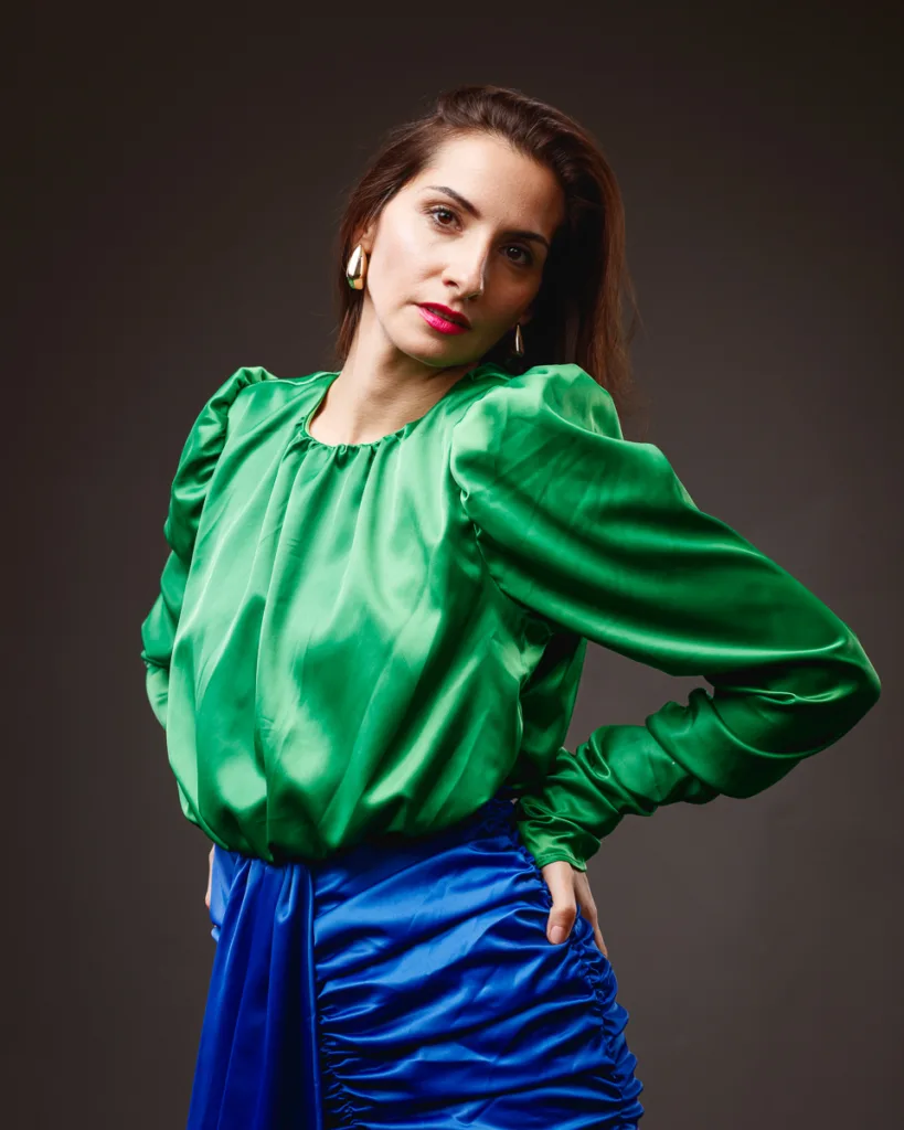Woman in green blouse and blue skirt posing.