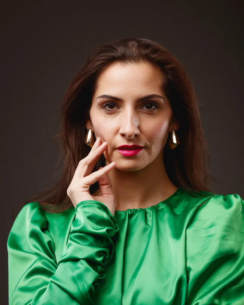 Person wearing green blouse and gold earrings.