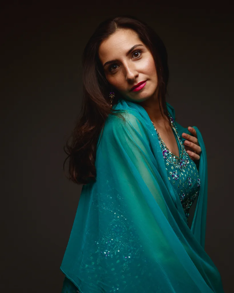 Woman in elegant turquoise dress and shawl.