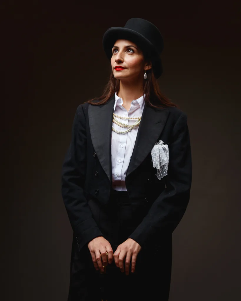 Woman in black suit and hat, looking upwards.