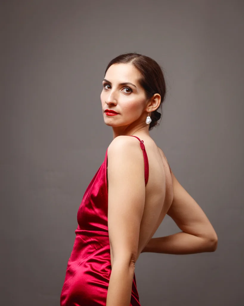 Woman in red dress poses confidently.