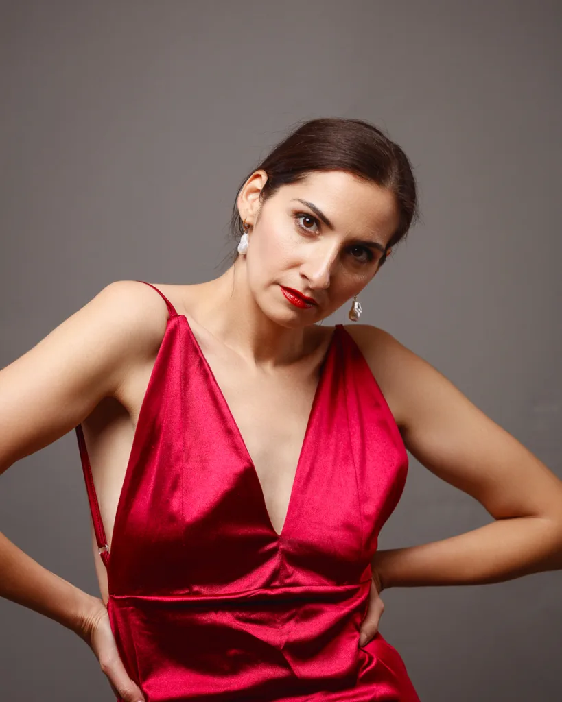 Woman in red dress posing confidently indoors.