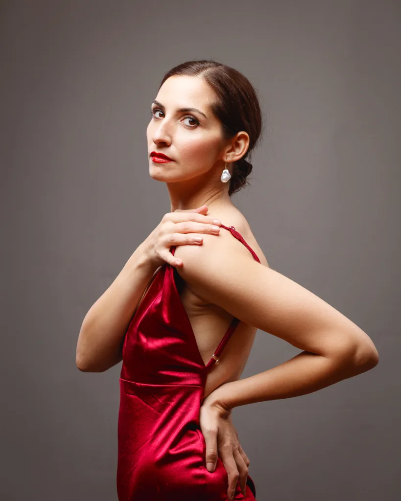 Woman in elegant red dress posing confidently.