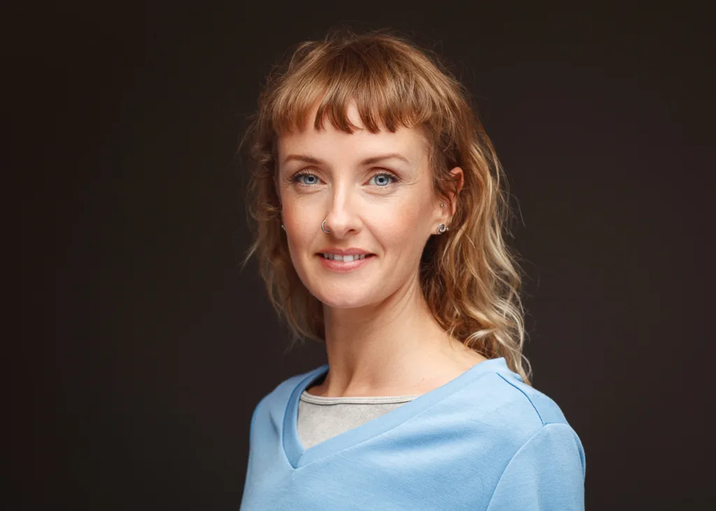 Smiling woman with curly hair and blue top.