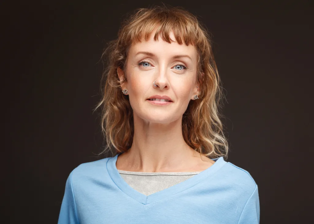 Woman with blue shirt, neutral background.