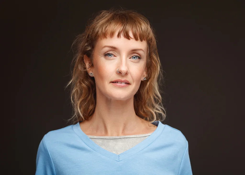 Smiling woman in blue top against dark background