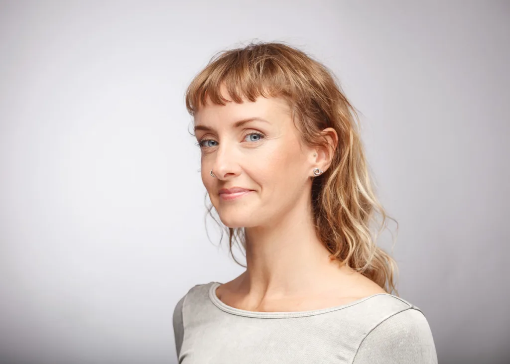 Woman with nose ring and earrings smiling.