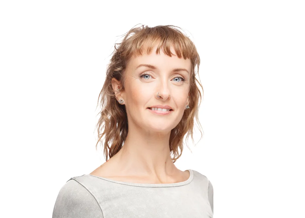 Smiling woman with wavy hair and nose ring.