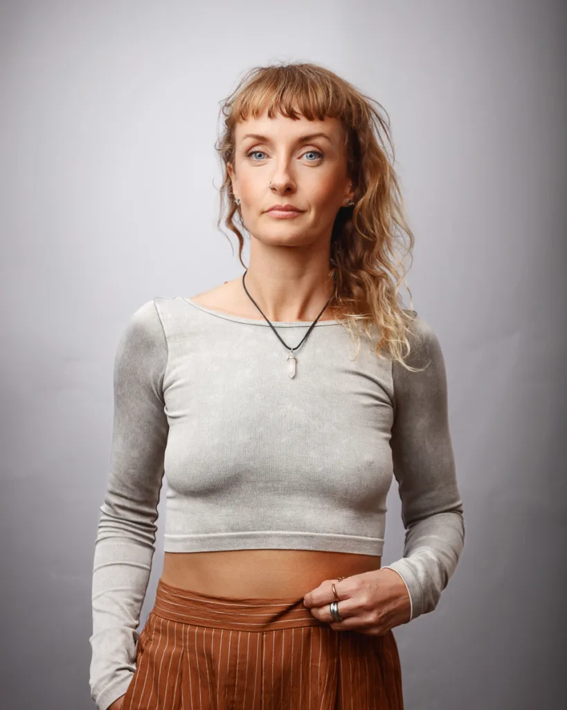 Woman posing in grey top, brown skirt.