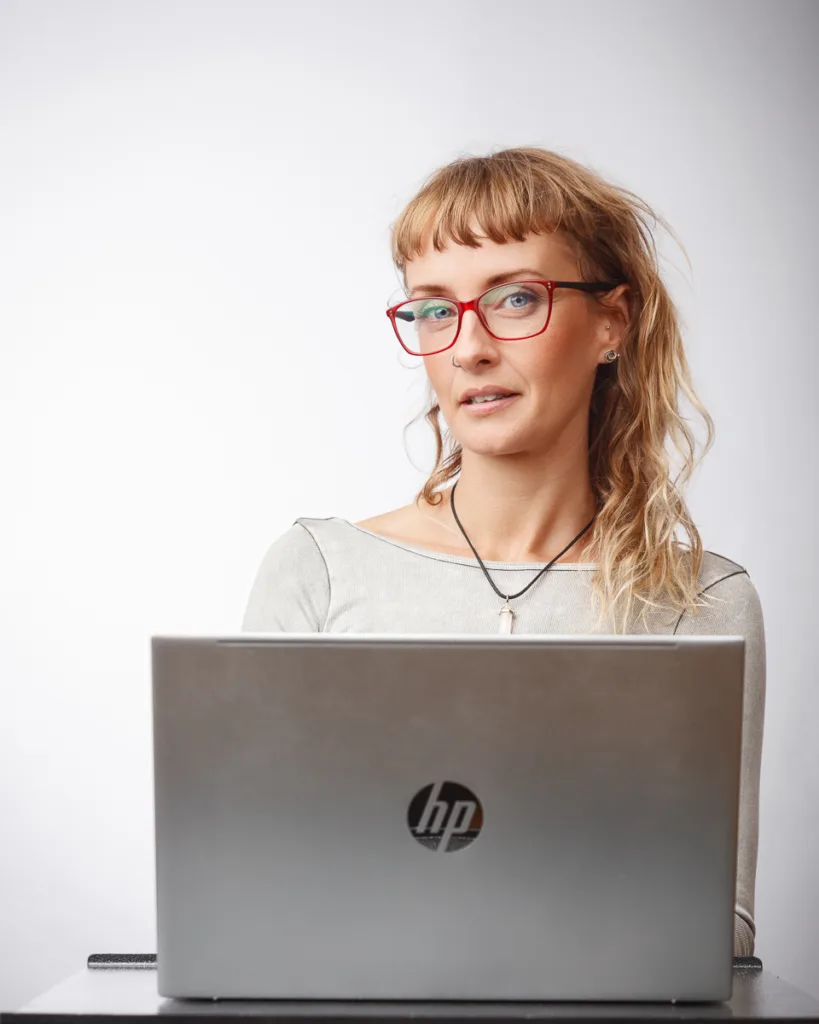 Person with laptop, red glasses, and casual attire.