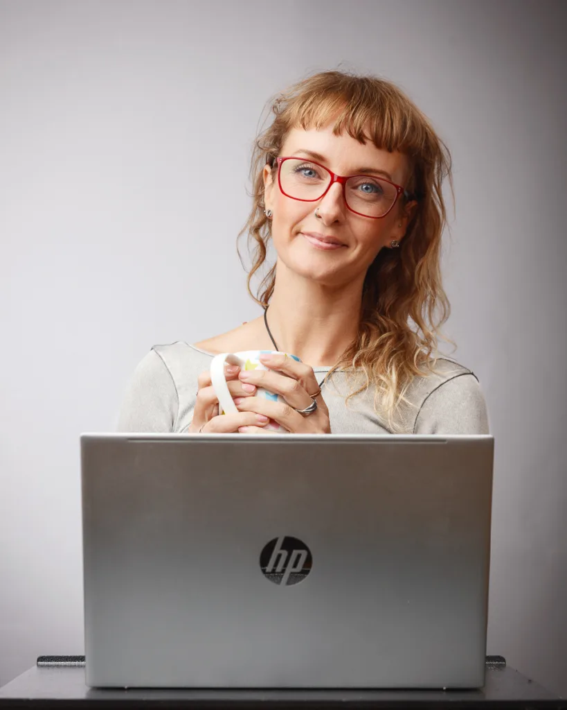 Person with laptop and mug, smiling indoors.