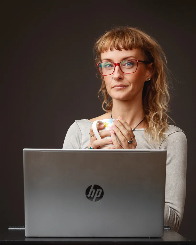 Person with mug and laptop in home office.
