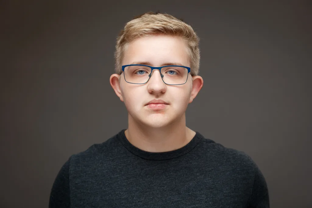 Person with glasses and blonde hair wearing dark shirt