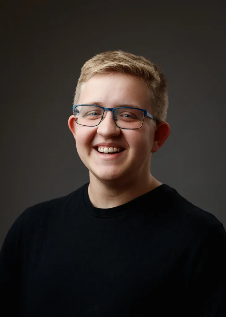 Person smiling with glasses, wearing a black shirt.