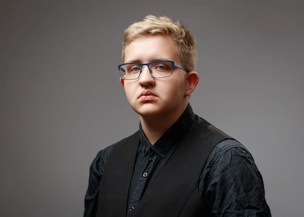 Person wearing glasses and black shirt, neutral expression.