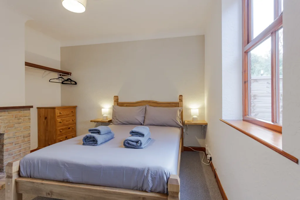 Cosy bedroom with double bed, pillows, and towels.