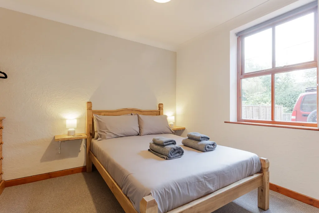 Cosy bedroom with double bed and wooden furniture.