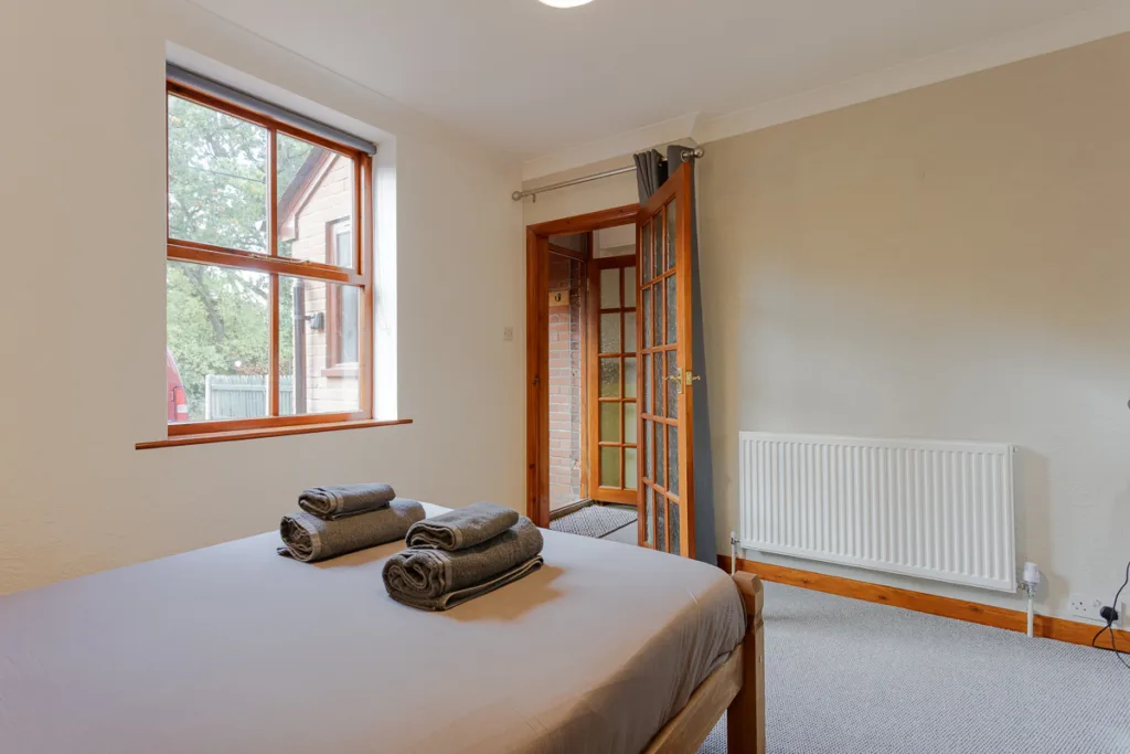 Cosy bedroom with window and towels on bed.