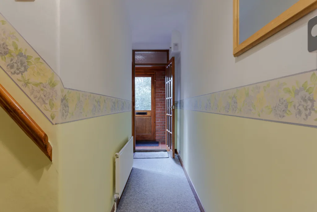 Hallway with floral wallpaper and open door view.