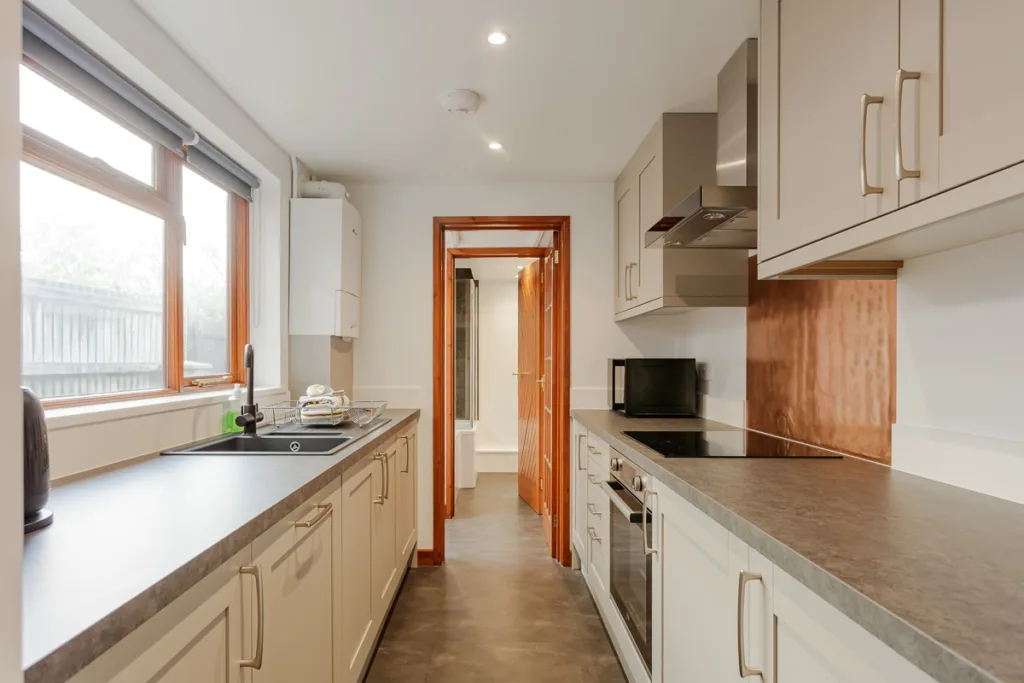 Modern kitchen with stove, sink, and wooden cabinets.