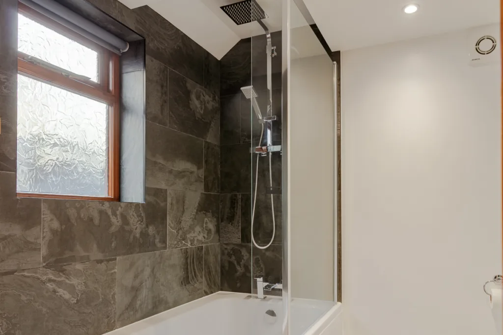 Modern bathroom with grey tiled shower and bath