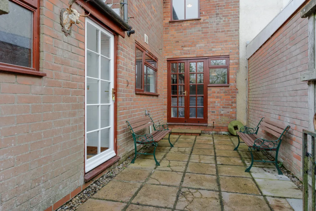 Brick patio with benches and glass doors.
