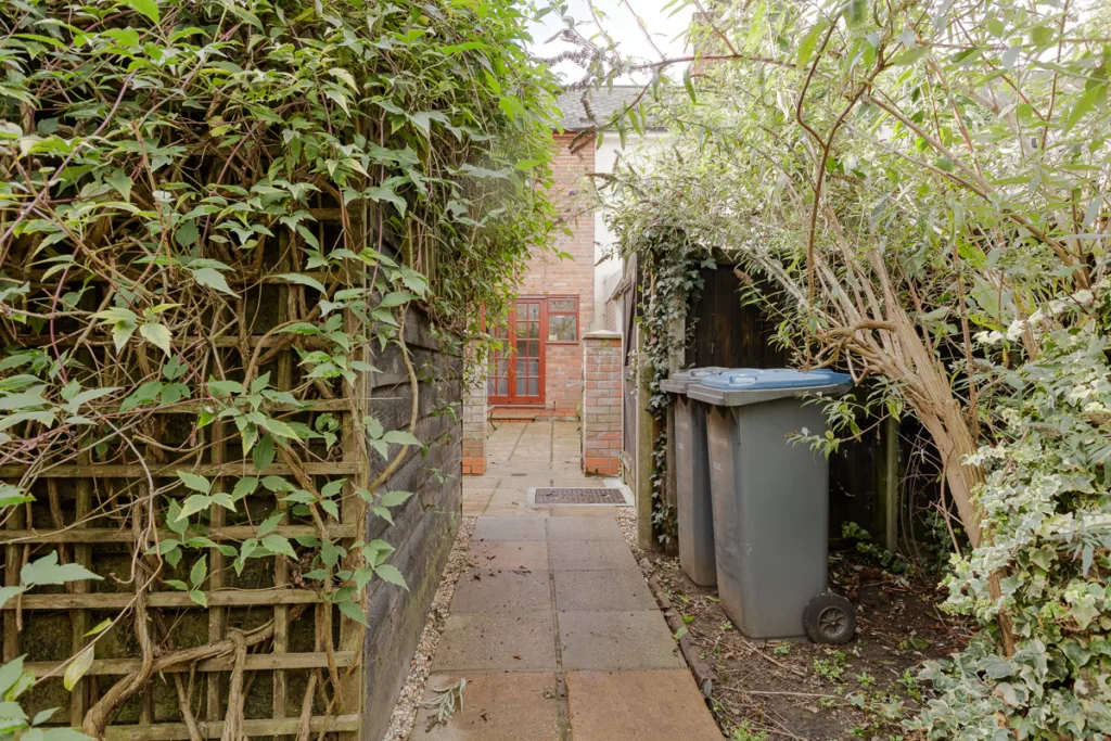 Narrow garden path with bins and foliage