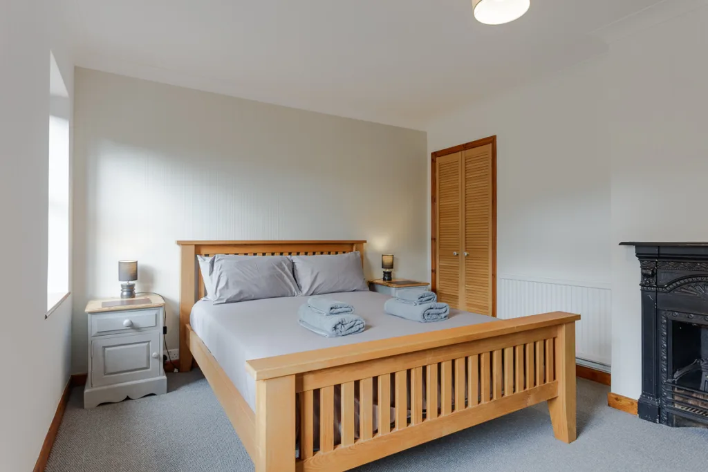 Minimalist bedroom with wooden bed and white walls.