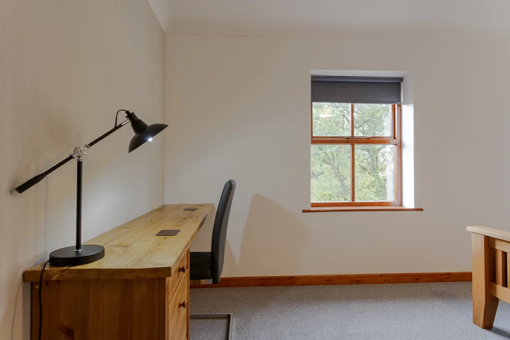 Minimalist home office with wooden desk and lamp.