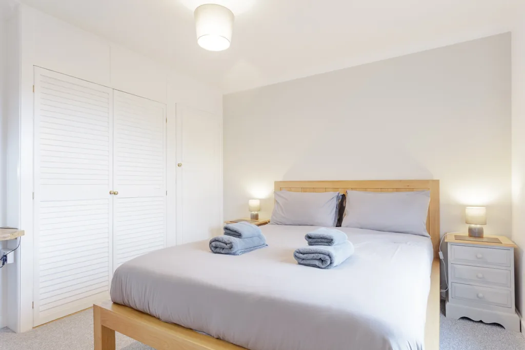 Modern bedroom with double bed and fresh towels.