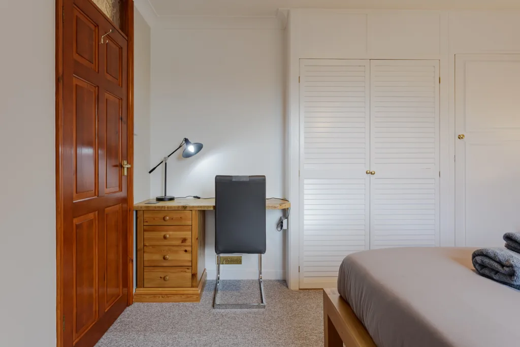 Minimalist bedroom desk setup with lamp and drawers.