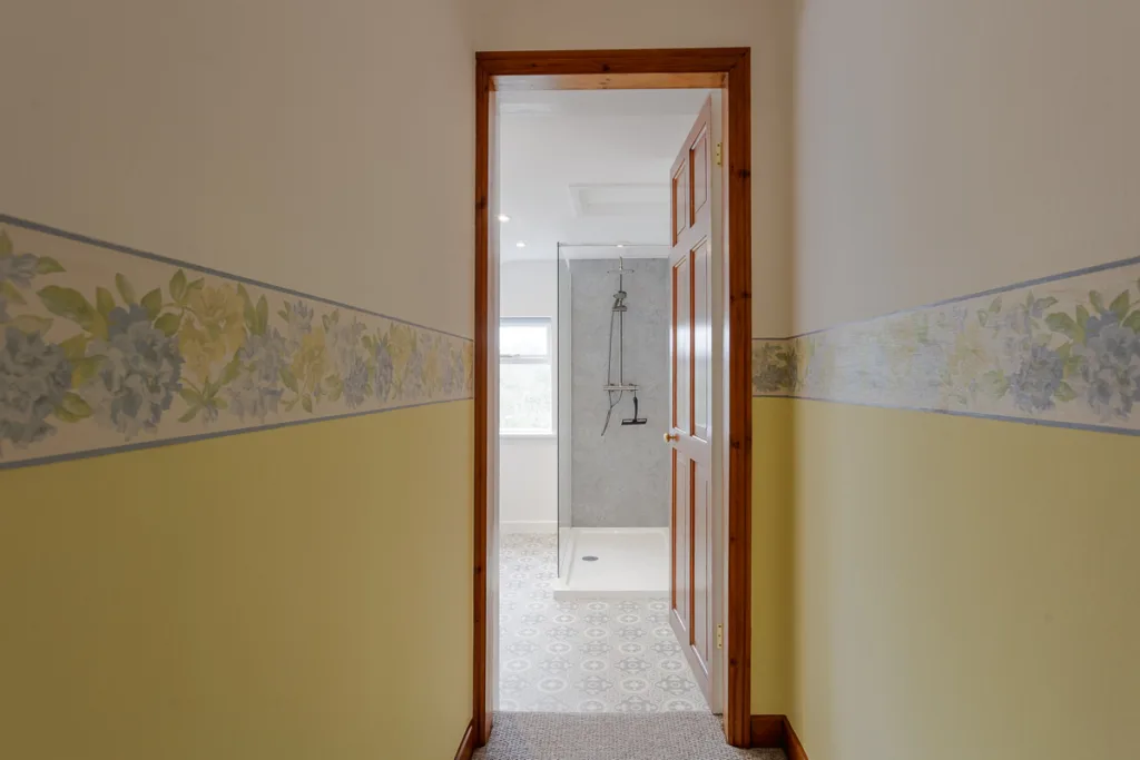 Hallway with floral wallpaper leads to bathroom.