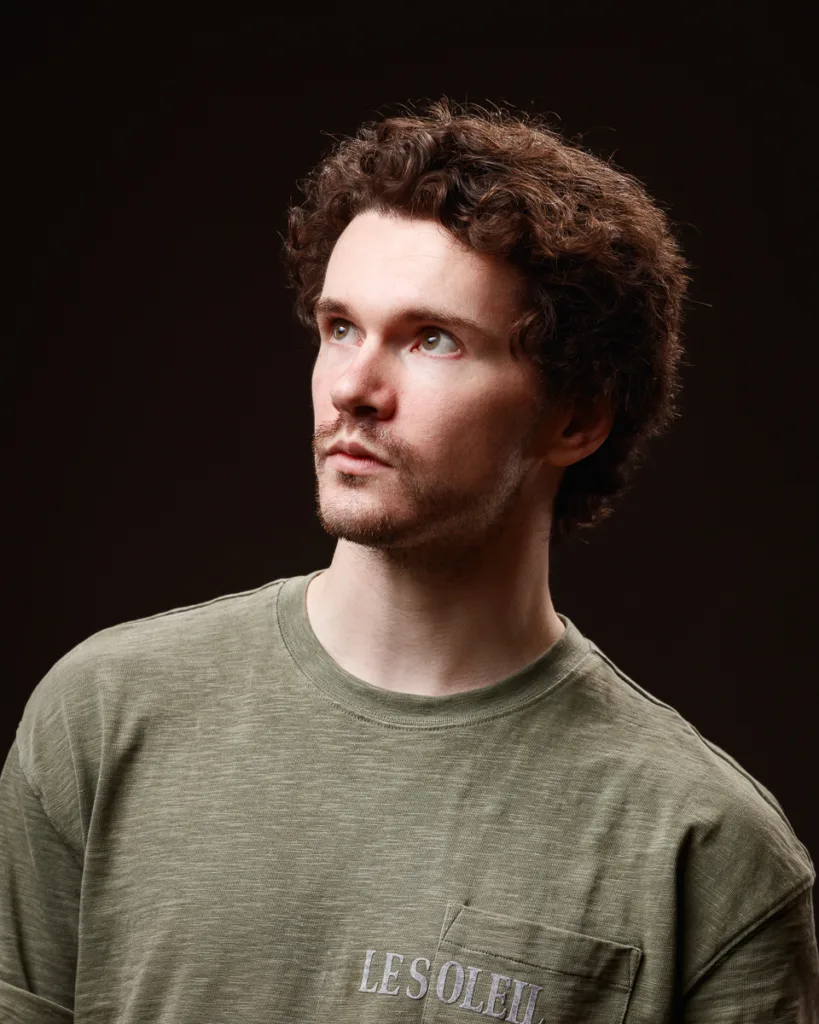 Man in green shirt looking upwards in studio.