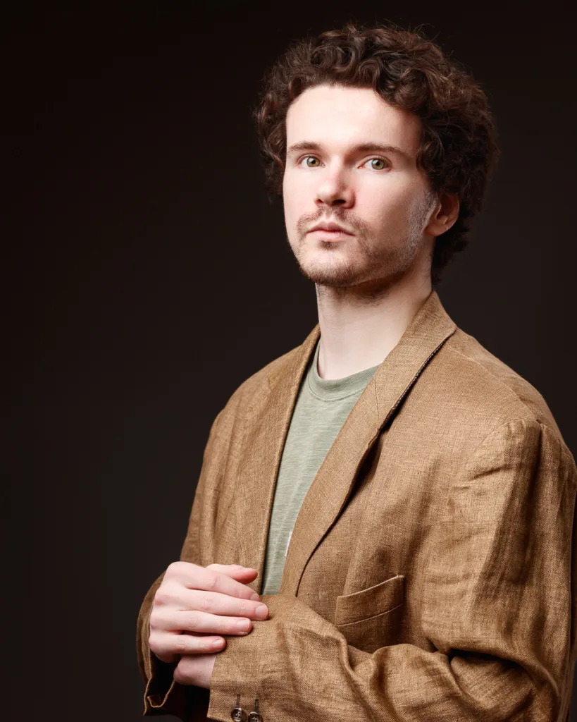 Man in brown jacket on dark background
