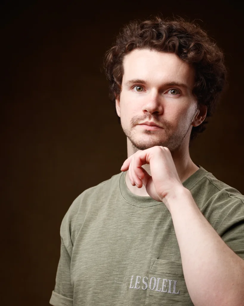 Man in green shirt posing thoughtfully.