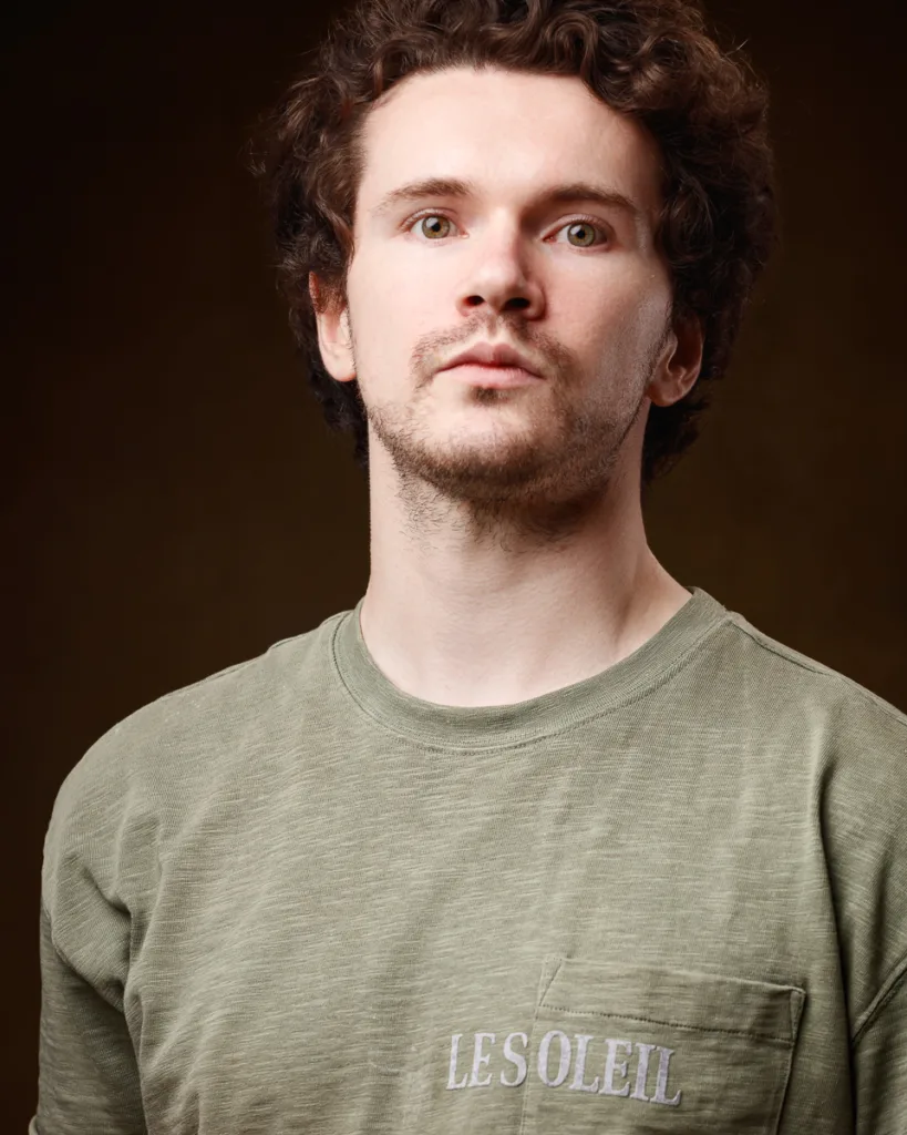 Man in green shirt with 'Le Soleil' print.