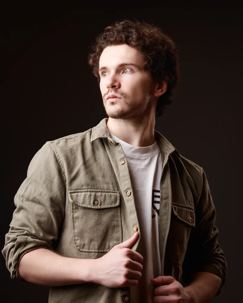 Man in olive shirt looks away thoughtfully.