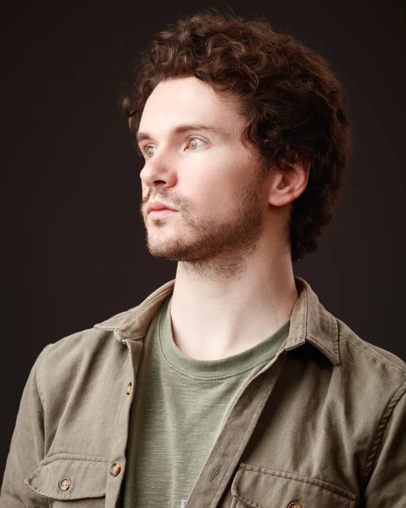 Person in profile wearing khaki shirt against dark background.