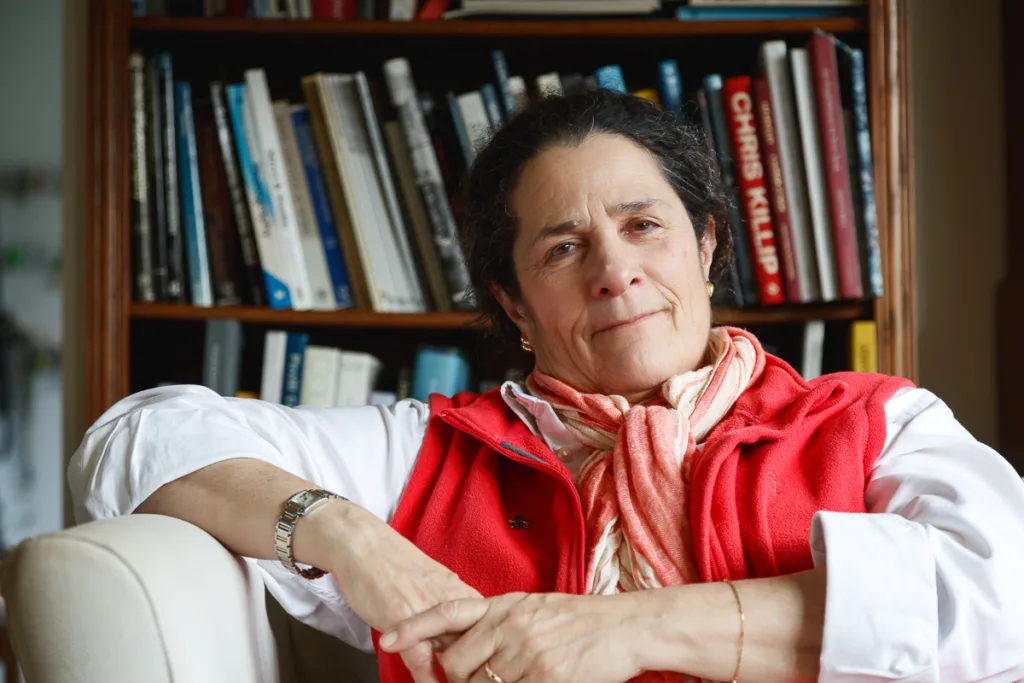 Person in red vest seated by bookshelf