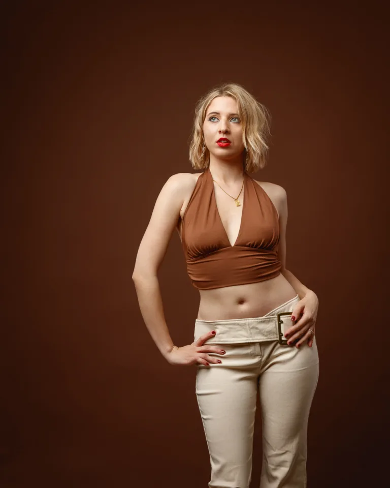 Woman posing against brown background, stylish outfit.