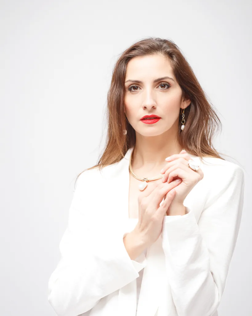 Woman in white jacket with jewellery.